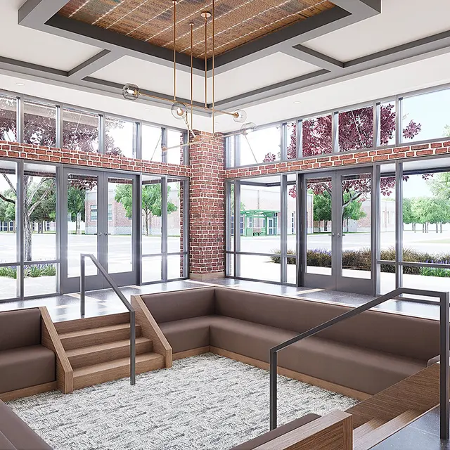 A spacious lobby area featuring brick walls, large windows, and contemporary seating arrangements.