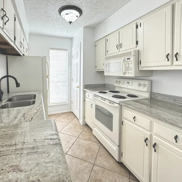 Interior view of a modern kitchen with white cabinets and granite countertops
