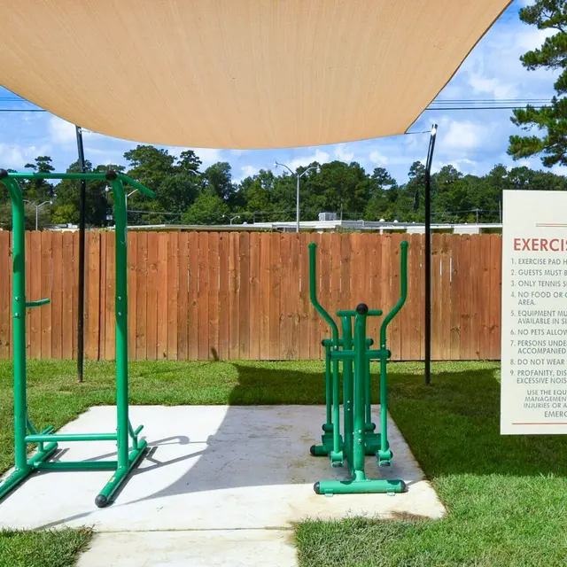 Outdoor exercise area with exercise equipment and a shaded canopy.