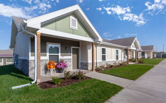 Modern Homes with Colorful Gardens Photo of a row of modern single-family homes with well-maintained lawns, colorful flower planters, and a clear blue sky.