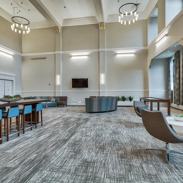 Modern Lounge Area A spacious lounge area with high ceilings, large windows, and multiple seating arrangements including a bar-height table and chairs, a circular couch, and lounge chairs.