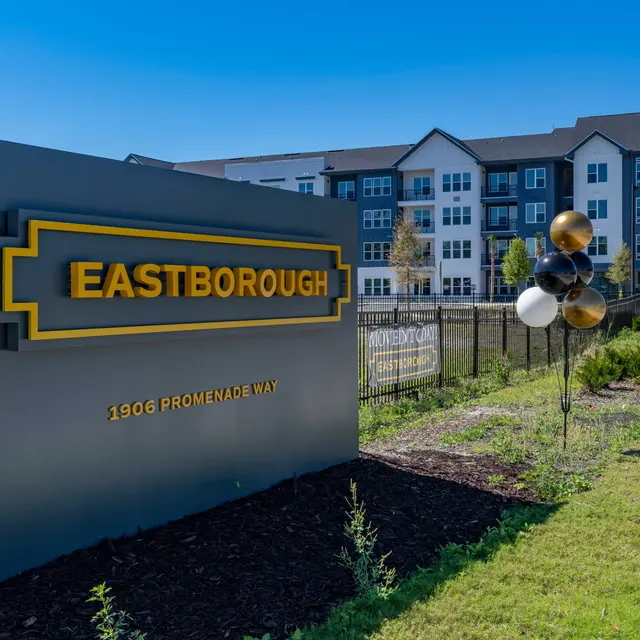 Sign for Eastborough at 1900 Promenade Way with balloons nearby and an apartment building in the background.