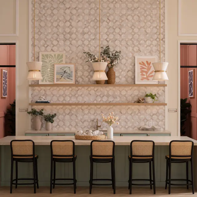 A stylish kitchen with a patterned wallpapered wall, wooden shelves holding decorative items, and a long table with chairs.