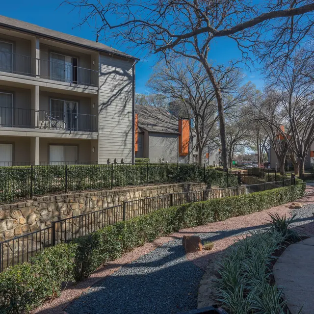 View of an apartment complex with a landscaped pathway and greenery.