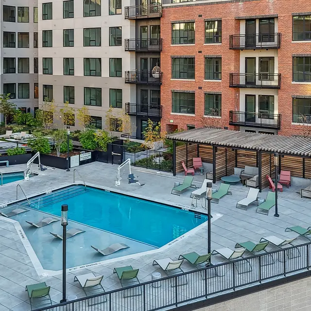 Modern Apartment Pool Area Aerial view of a modern apartment complex with a spacious pool area surrounded by lounge chairs and greenery.