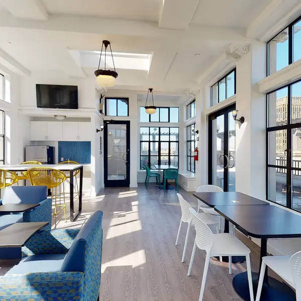 A bright, modern lounge area with large windows, comfortable seating, and tables.
