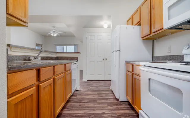 Contemporary Kitchen Overview Bright modern kitchen featuring wooden cabinets, white appliances, and a spacious layout with a door leading to another room.