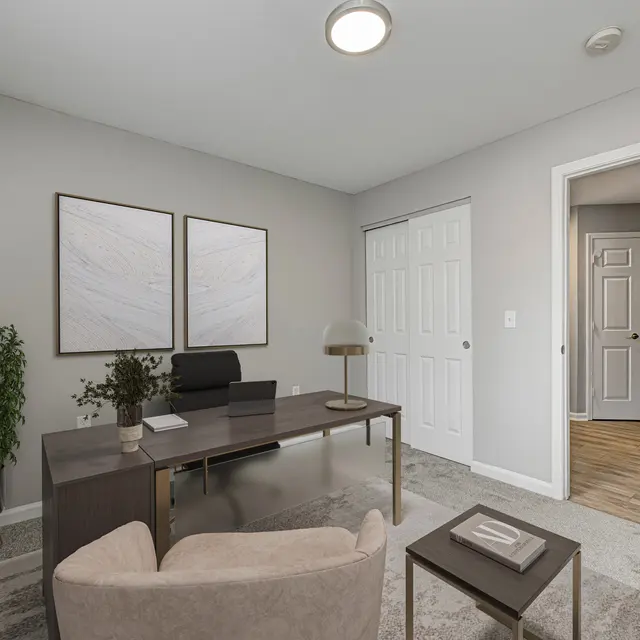 A modern home office featuring a sleek desk, comfortable chair, and decorative plant with two abstract artworks on the wall.