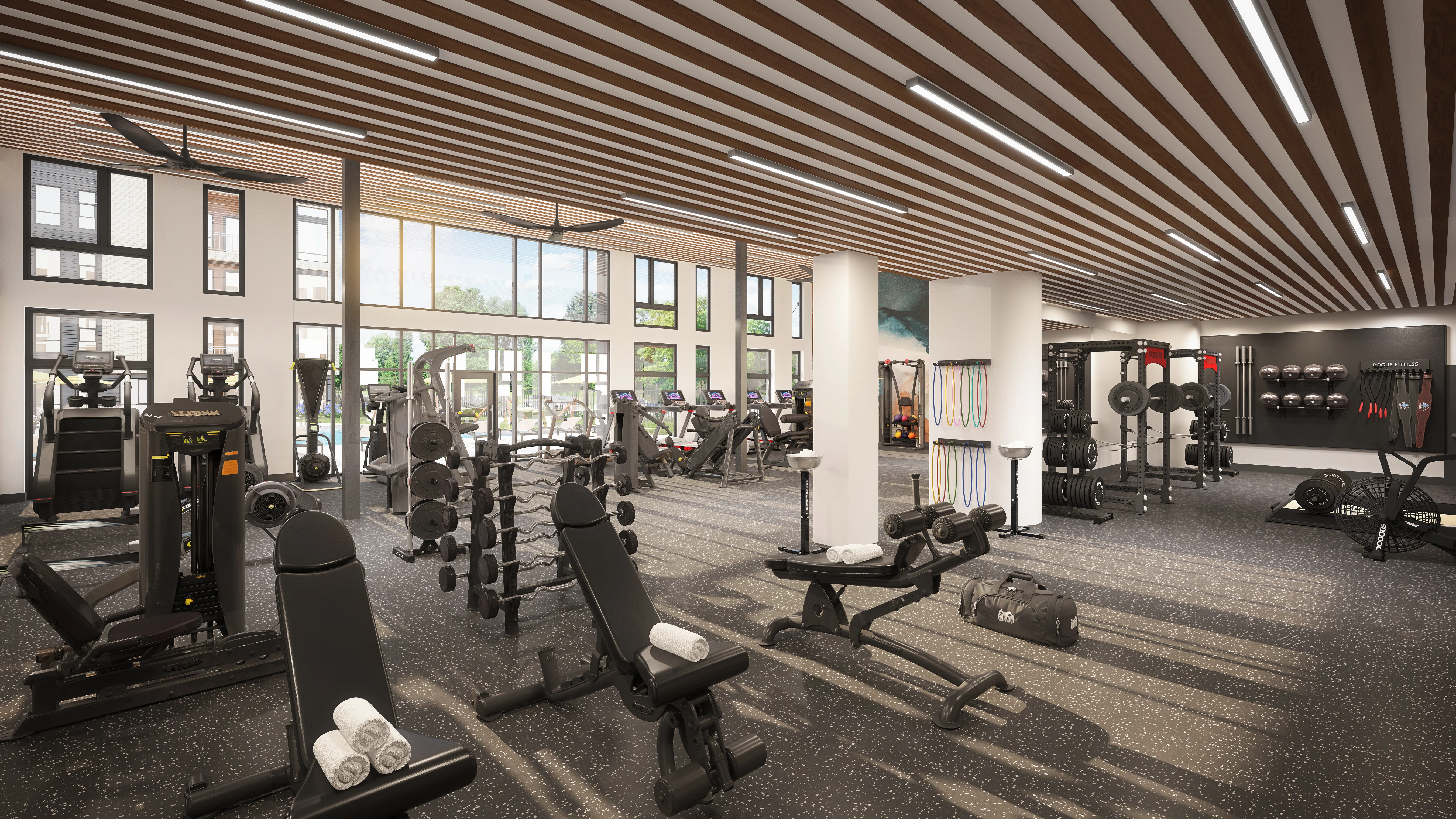 Interior of a Modern Gym A spacious, modern gym interior with various fitness equipment, including weight machines and benches. Large windows provide natural light, and the ceiling features wooden beams.