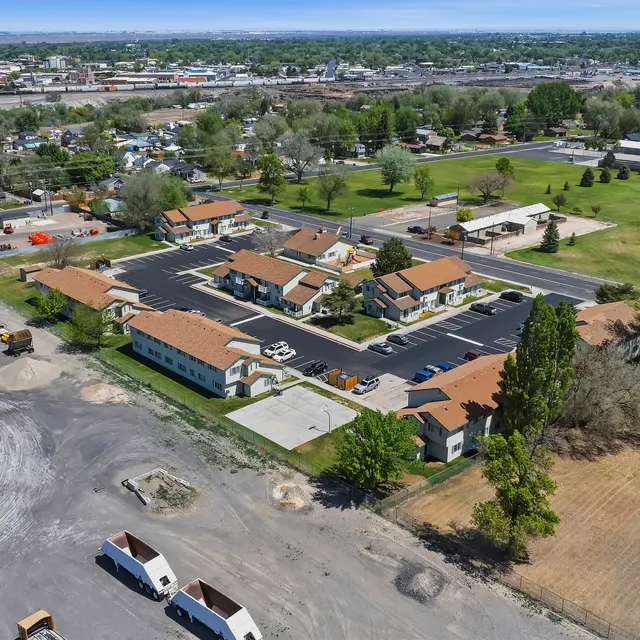 Aerial View of Residential Complex Aerial view of a residential area featuring multiple buildings, parked vehicles, and green spaces.