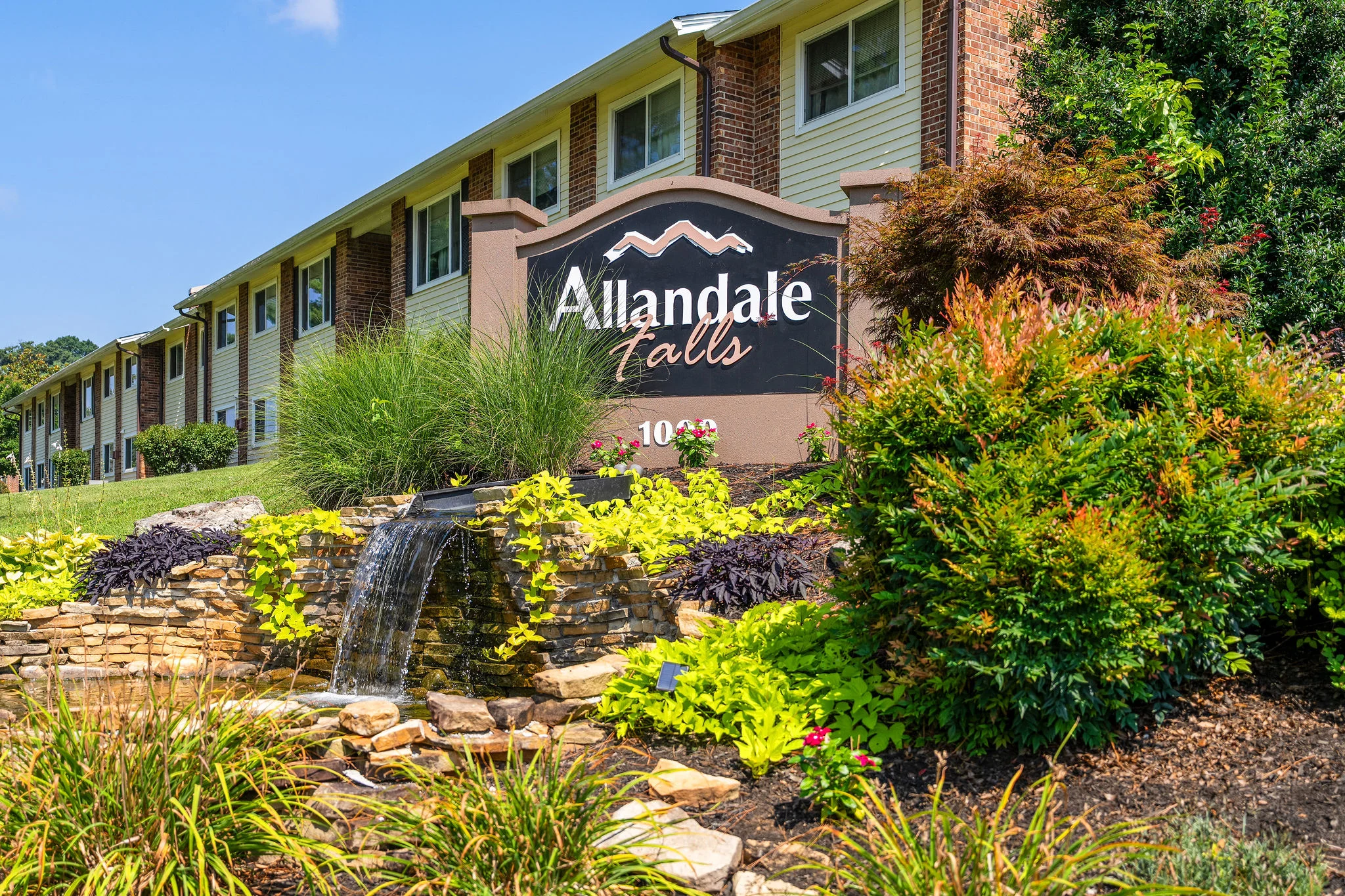 Exterior view of Allandale Falls apartment complex with landscaped gardens and water feature.