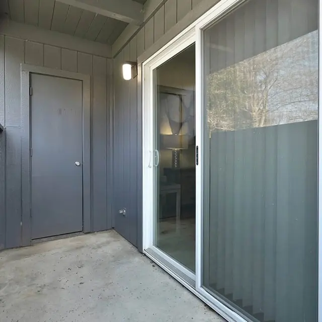 A view of an apartment balcony with a gray exterior and sliding glass door.
