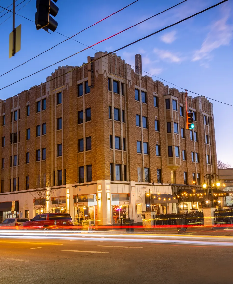 Art Deco Historic Building at Twilight A historic building with an Art Deco style on a city street during twilight, featuring warm lighting and a light trail from passing cars.