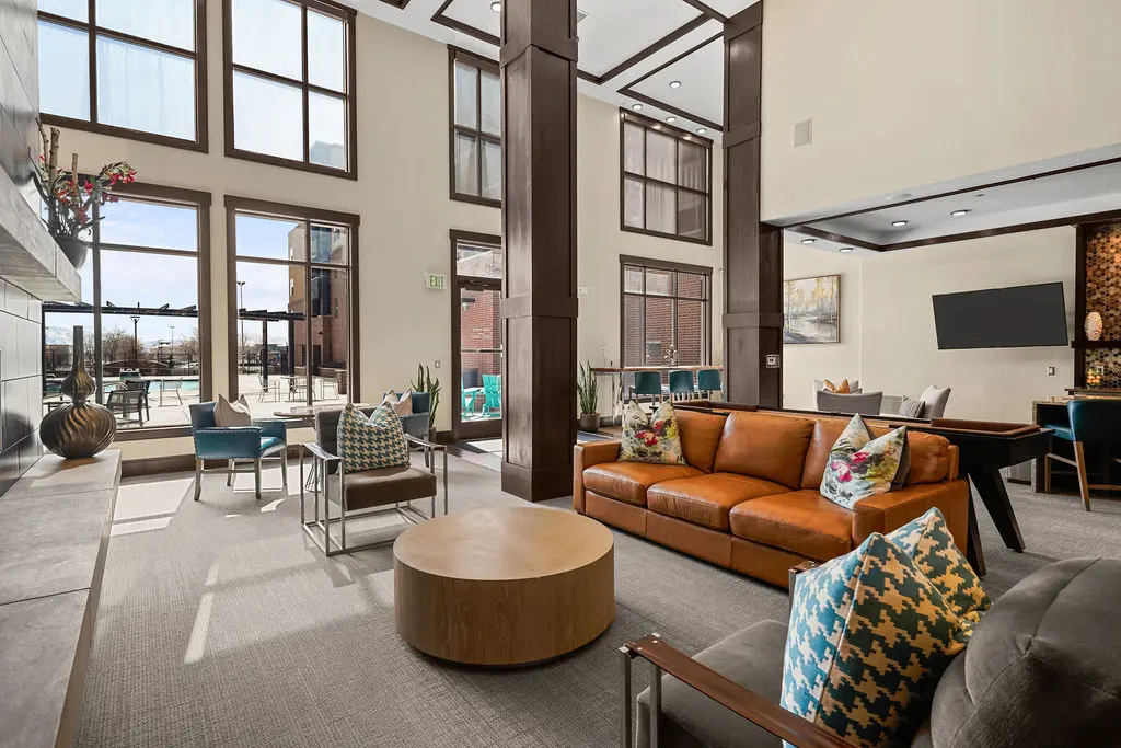 A spacious and stylish modern living room with large windows, comfortable seating, and decorative pillows.