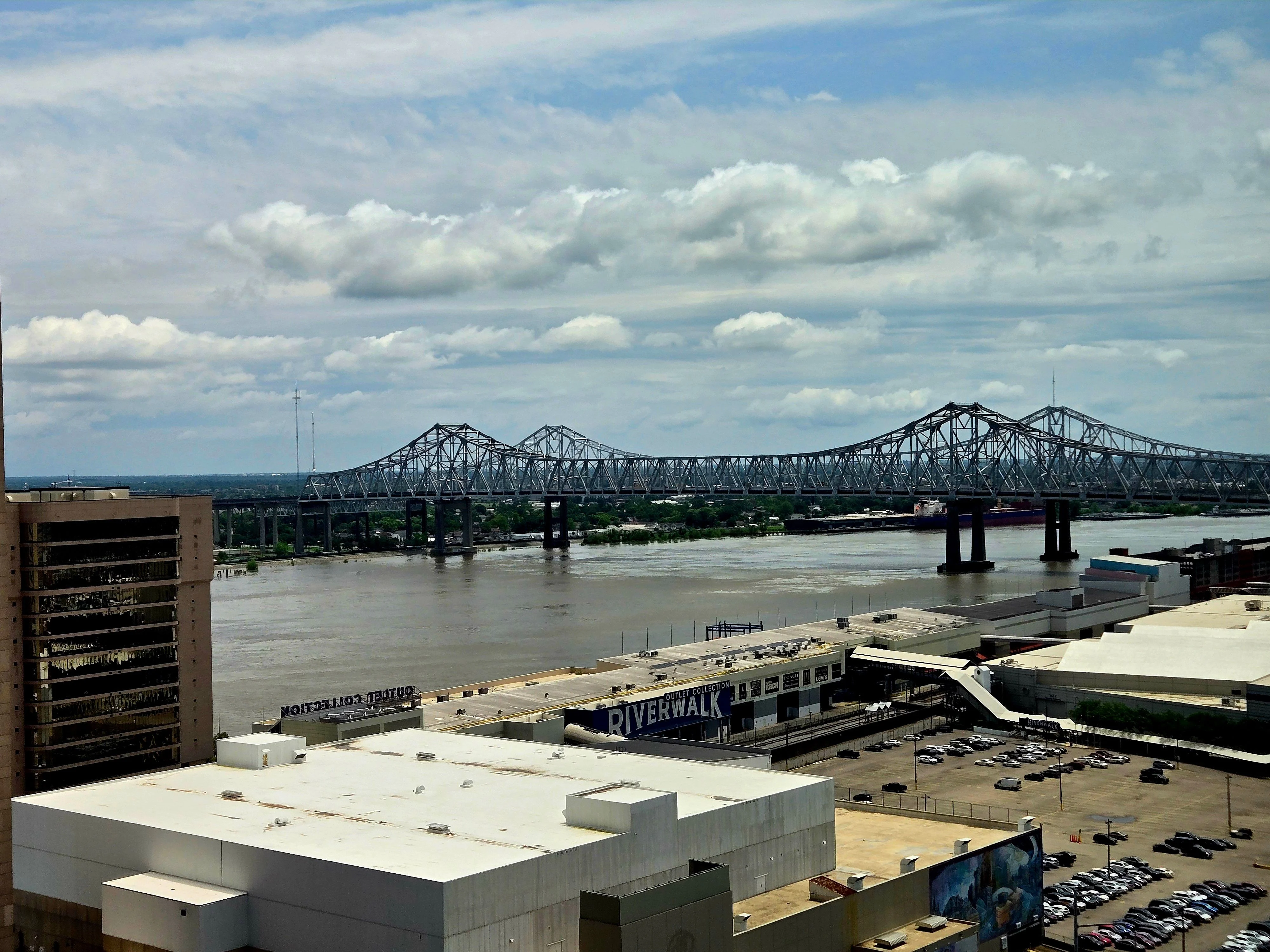 A view of a large bridge spanning a river with a cityscape in the foreground.