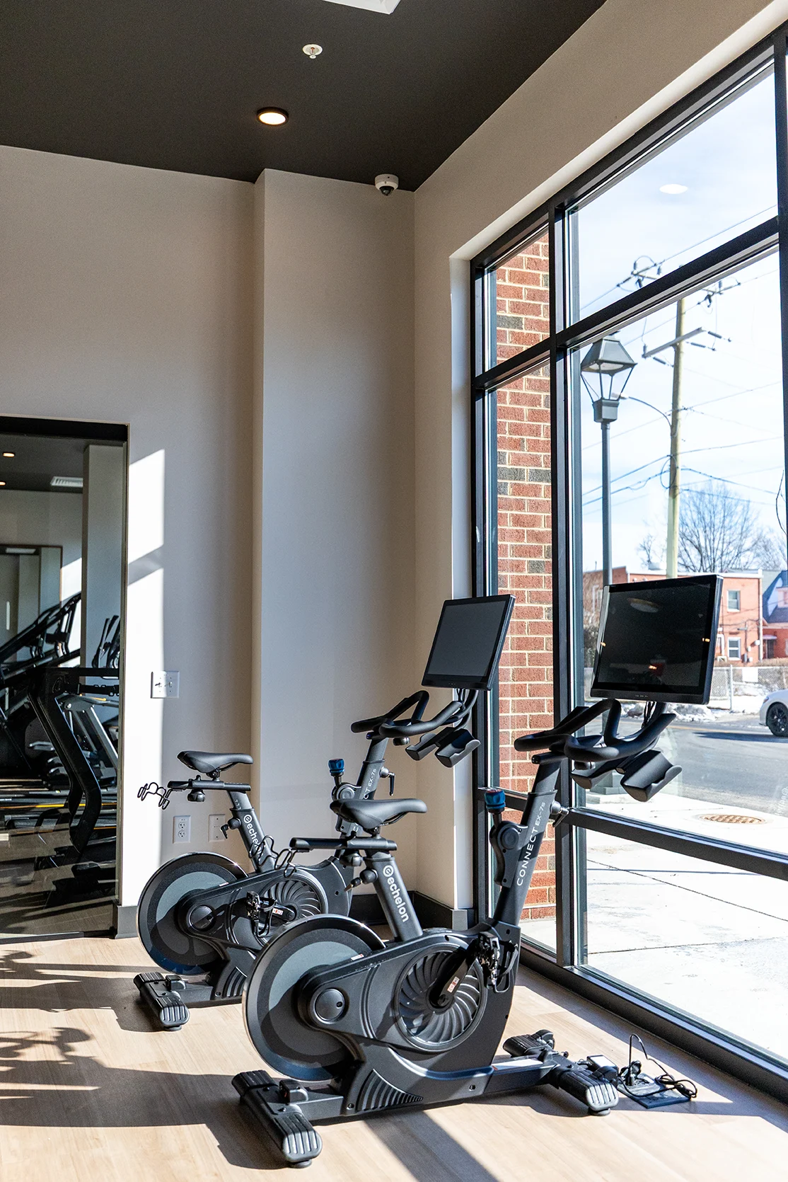 Modern Gym with Stationary Bikes Two modern stationary bikes positioned near large windows in a gym, with natural light illuminating the space.