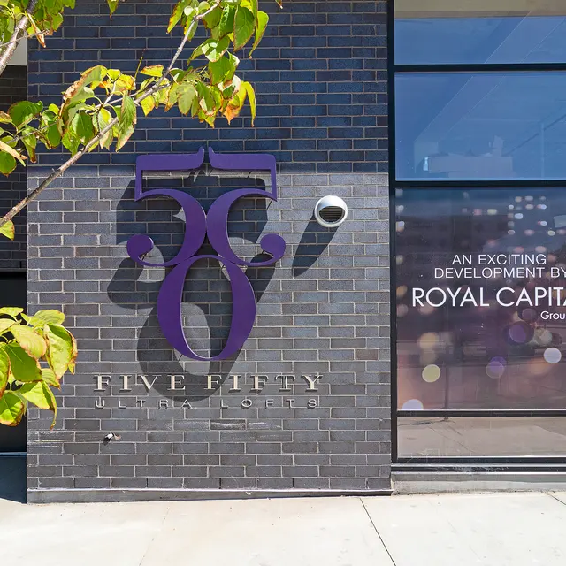 Exterior view of a building featuring a sign that reads 'Five Fifty Ultra Lofts' and promotional text for Royal Capital Group LLC.