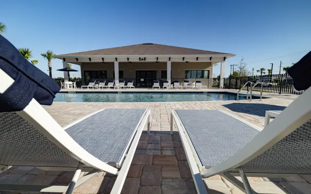 Two lounge chairs by a pool with a modern building in the background