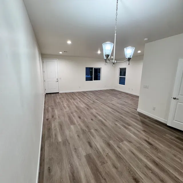 Modern Living Room Interior A spacious modern living room with wooden floors, a chandelier, and large windows illuminating the space.
