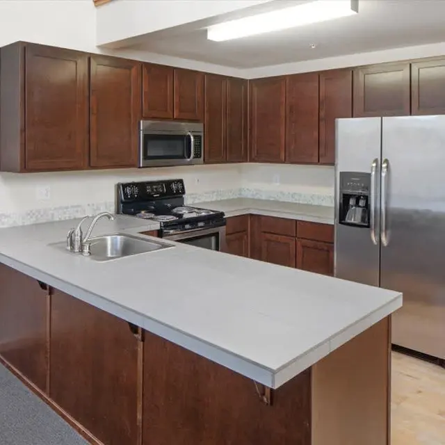 A modern kitchen with dark wood cabinets, stainless steel appliances, and a large countertop island with a sink.