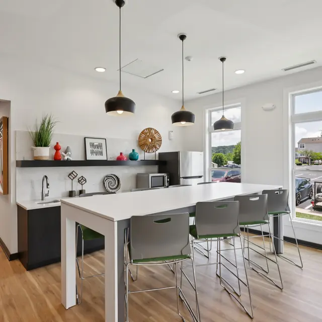 Modern Kitchen Area A modern kitchen area with a large white table and high stools, pendant lights, and a window showcasing outdoor views.