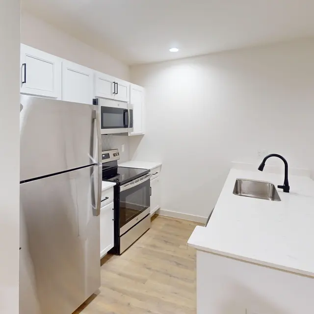 A modern kitchen featuring stainless steel appliances, white cabinets, and a central island with a sink.