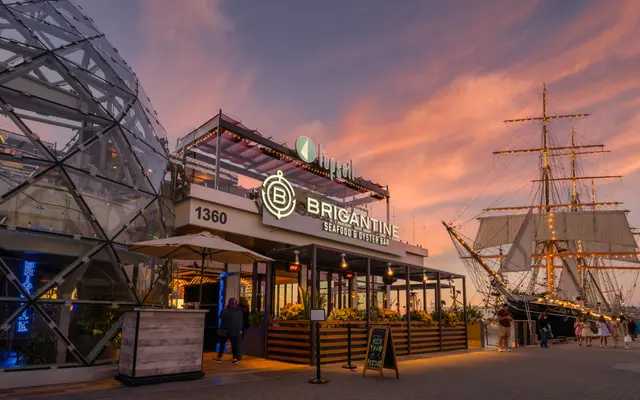 The Brigantine seafood restaurant at sunset with a tall ship in the background.