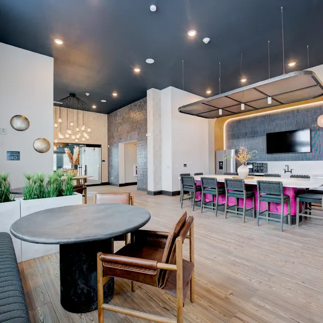 Interior view of a modern communal space with seating and kitchen area.