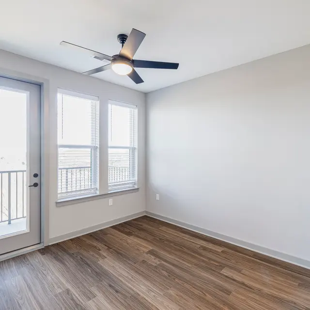 Interior view of a modern apartment with a fan and large windows