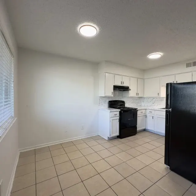 Modern Kitchen Design A modern kitchen featuring white cabinetry, black appliances, and a tiled floor.