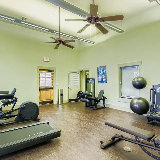 Interior of a fitness room featuring exercise equipment and natural lighting.