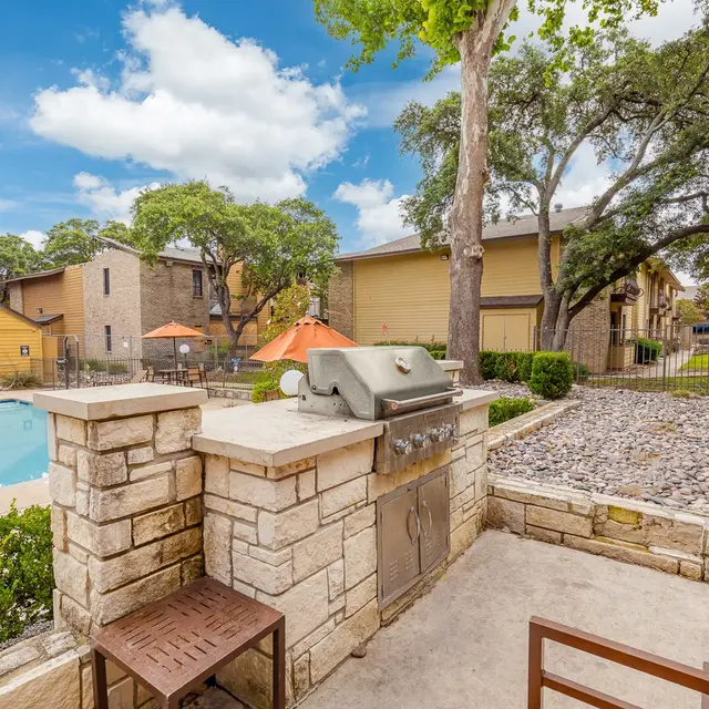 Outdoor area with a built-in grill near a swimming pool and landscaped garden