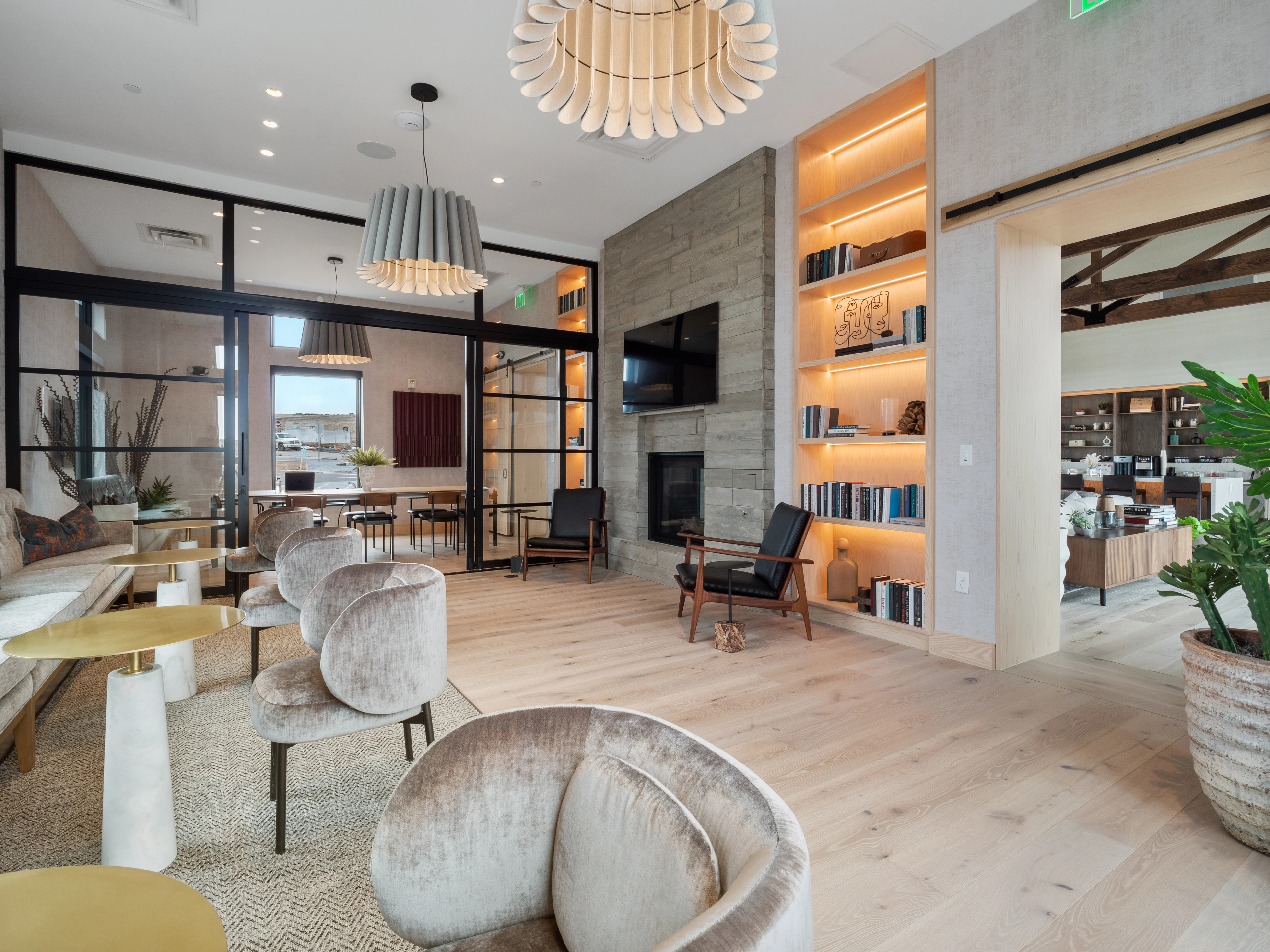 Modern Lobby Design An elegant modern lobby featuring plush seating, a warm color palette, and a stylish bookshelf. The space is well-lit with contemporary light fixtures and has large windows allowing natural light to flood the room.