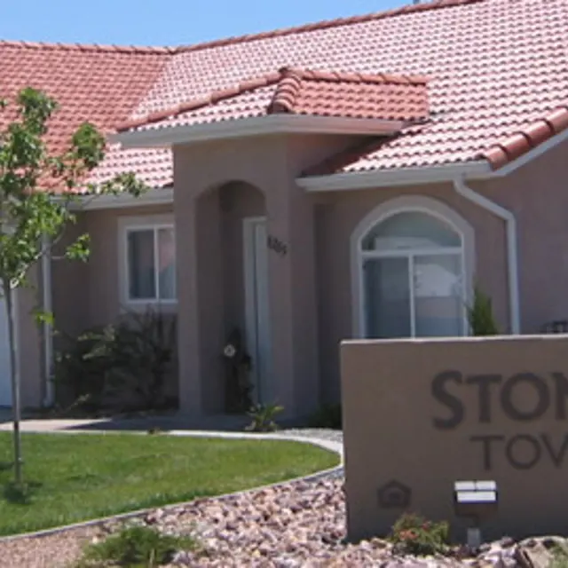 View of Stone Ridge Townhomes with a landscaped front yard and clear blue skies.