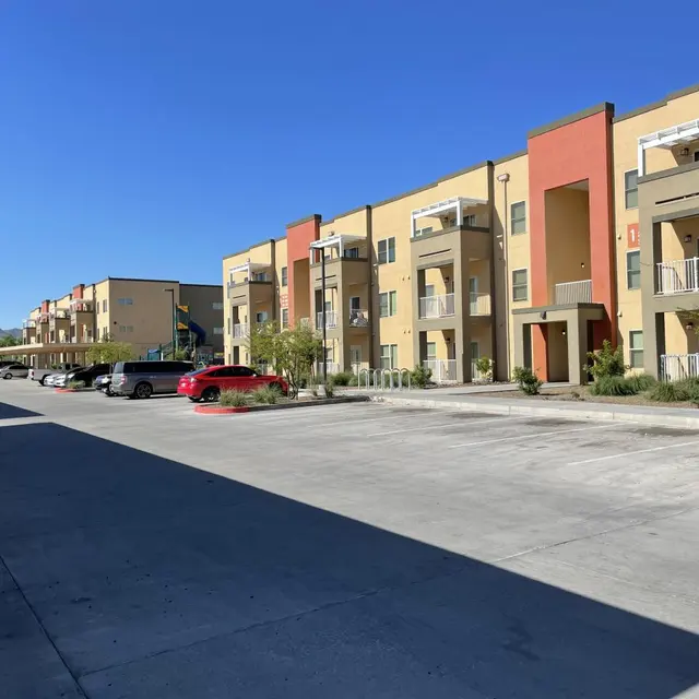 View of an apartment complex with colorful buildings and a parking lot under clear blue skies.