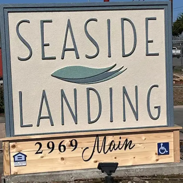 A large sign displaying the text 'SEASIDE LANDING' with a stylized wave graphic, located at 2969 Main. The sign includes accessibility symbols.