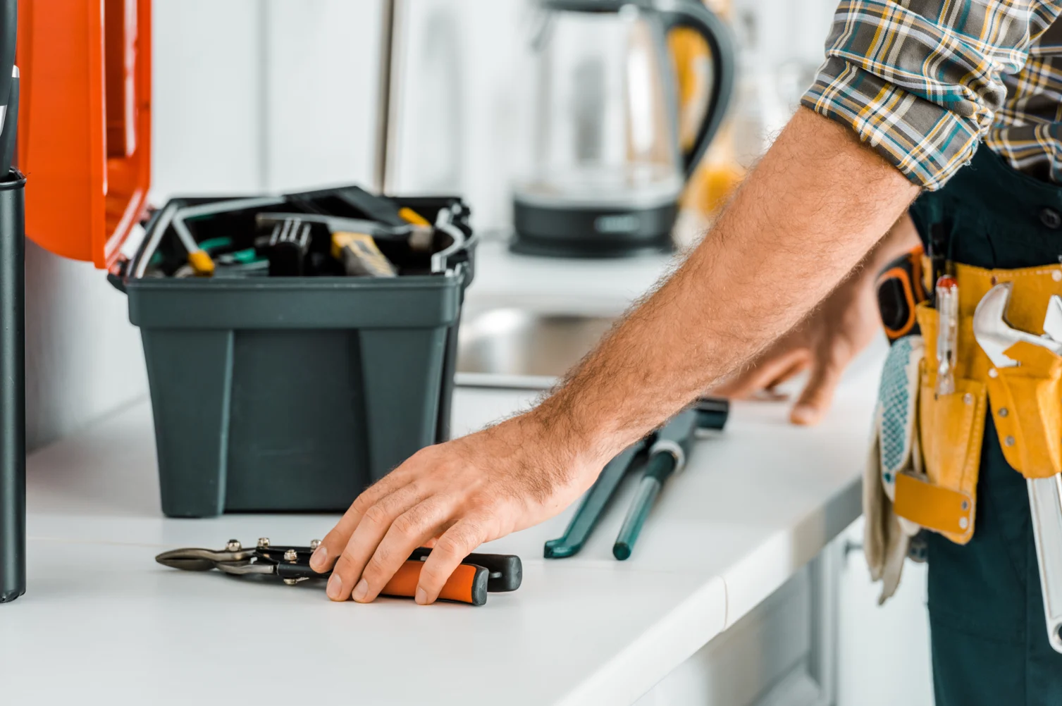 Handyman Tools in Workshop A person reaching for a tool on a workbench with a toolbox in the background.