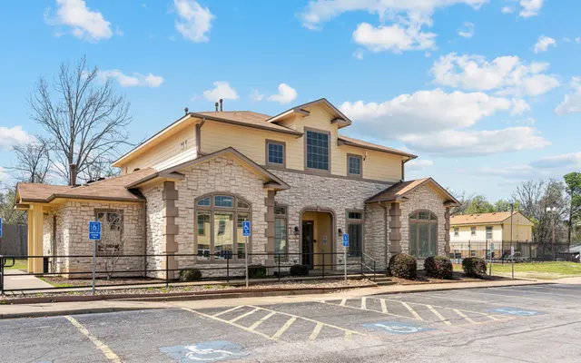 Modern Building Exterior Exterior view of a multi-story building with stone and wood facades, featuring parking spaces in front.