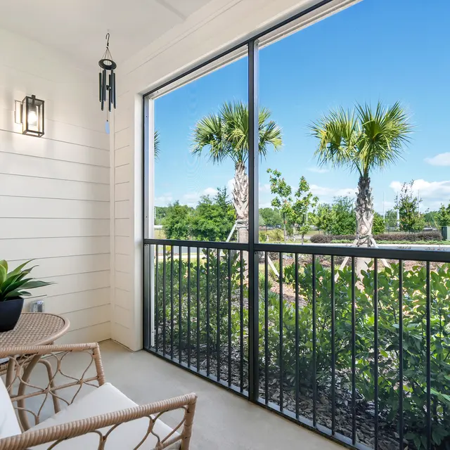Serene Balcony with Scenic View A modern balcony with two rattan chairs and a potted plant overlooking greenery and palm trees under a blue sky.
