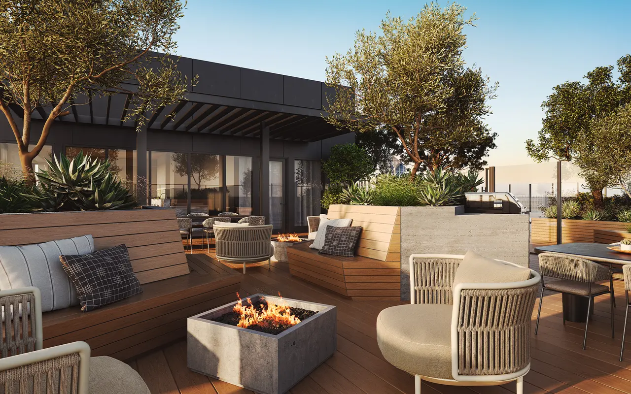 A stylish rooftop lounge area with modern seating, a fire pit, and greenery.