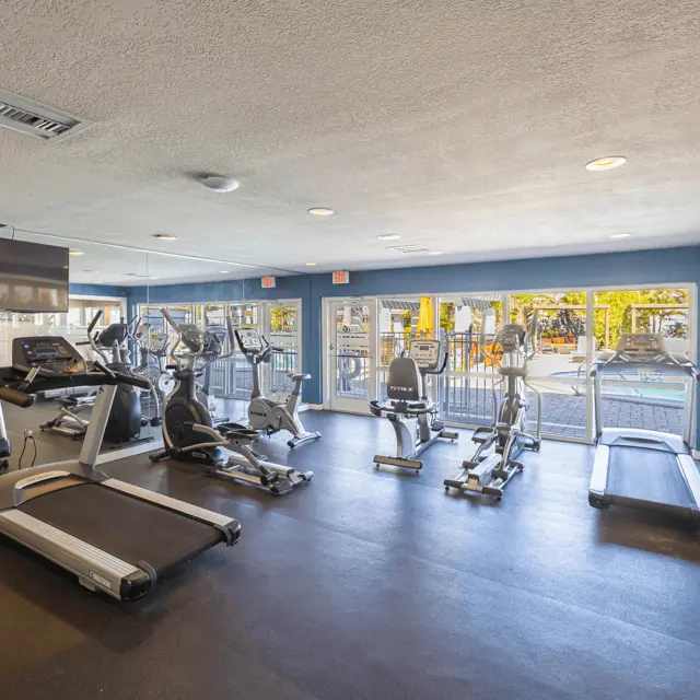 Interior view of a modern gym with exercise equipment including treadmills and stationary bikes.