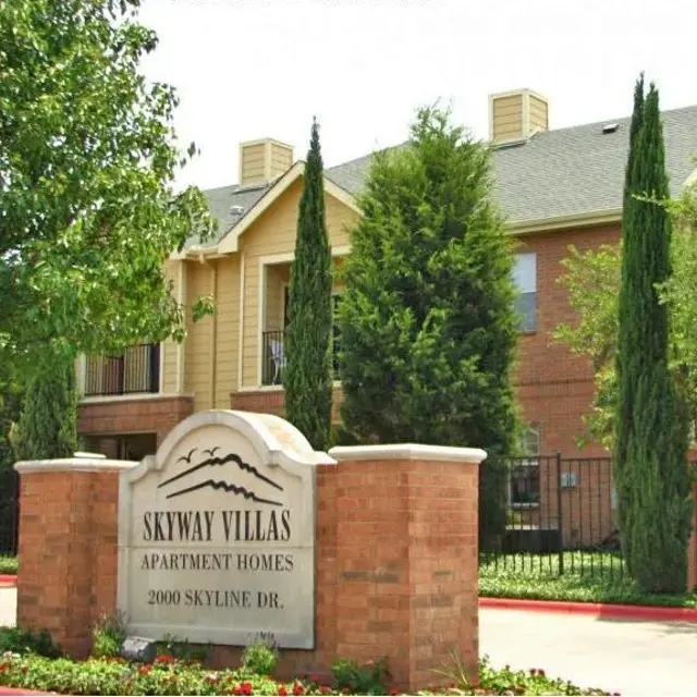 Exterior view of Skyway Villas Apartment Homes with a sign and surrounding greenery