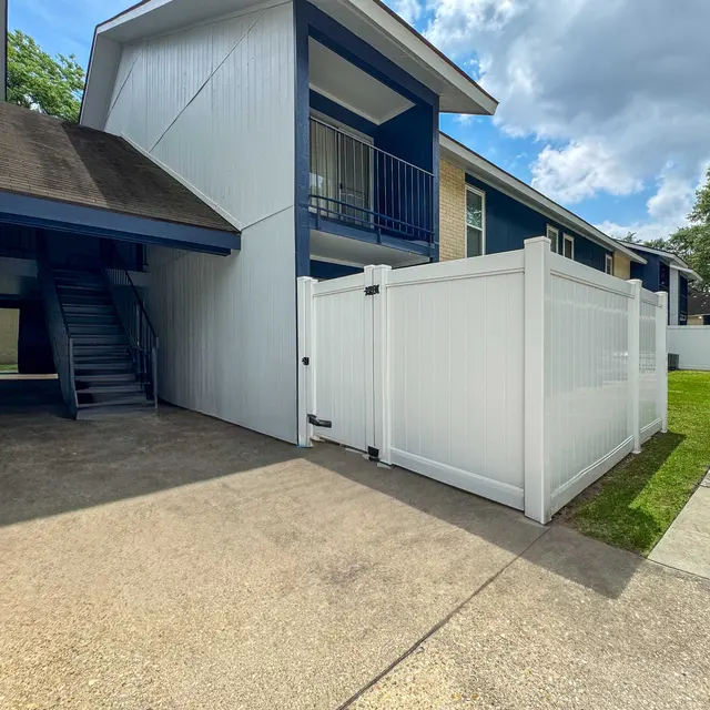 Exterior view of an apartment complex with a staircase and a fenced area