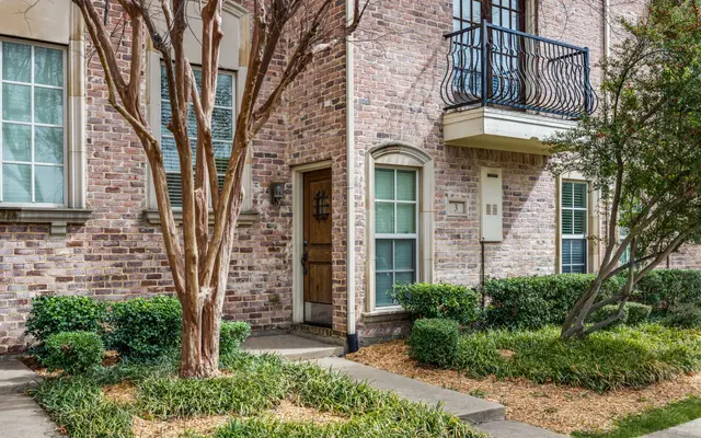 Charming Brick House Entryway A brick house entryway with a wooden door, small porch, and balcony above.