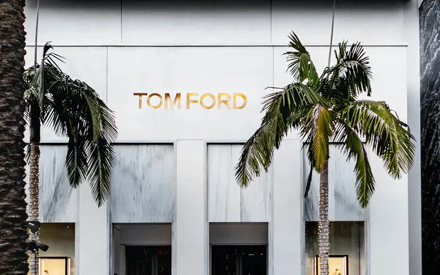 Exterior view of a Tom Ford retail store with palm trees in front.
