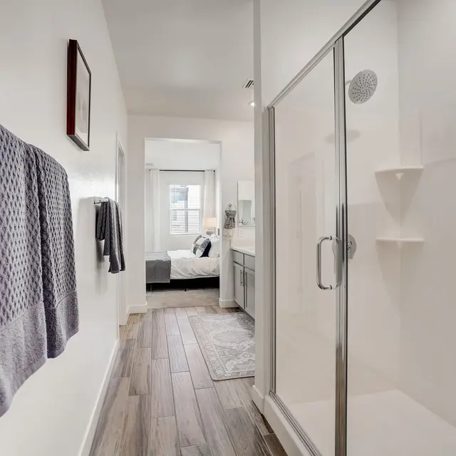 Contemporary Bathroom Interior A modern bathroom featuring a clear glass shower. Towels hang on a rack on the left side, and there is a view into a bedroom beyond.