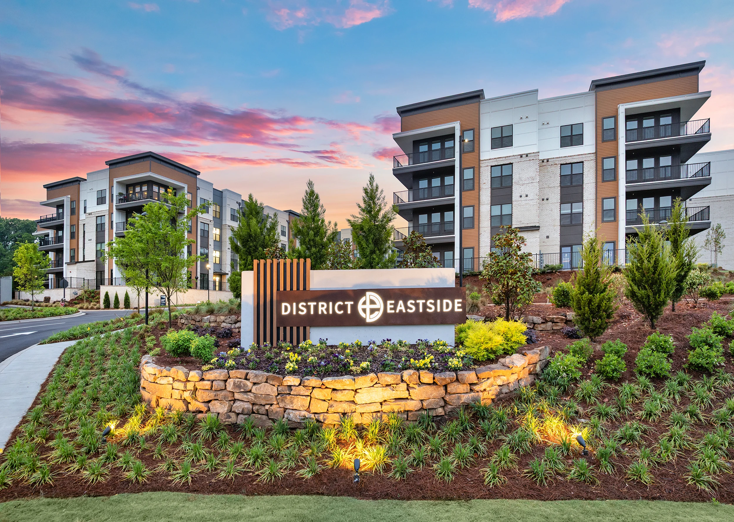 Exterior view of a modern apartment complex with landscaping and a sign reading 'District Eastside.'
