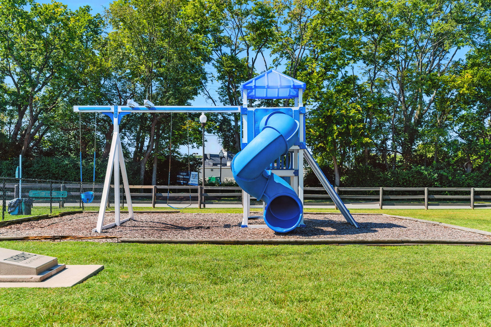 Children's Playground with Slide and Swings A playground featuring a blue slide and swings surrounded by grass and trees.