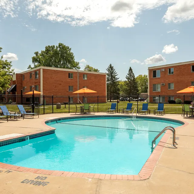 Regency Park - Outdoor swimming pool area at an apartment complex featuring lounge chairs and umbrellas.