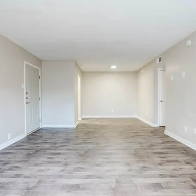 An empty living room in an apartment with a light-colored wall and modern flooring.